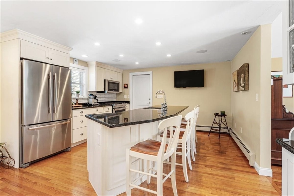 7 Peter Hobart Drive Hingham, MA 02043 - Photo 10 of 38 a kitchen with stainless steel appliances granite countertop a refrigerator a stove top oven a sink dishwasher a dining table and chairs with wooden floor