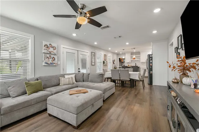a living room with furniture and a flat screen tv with kitchen view