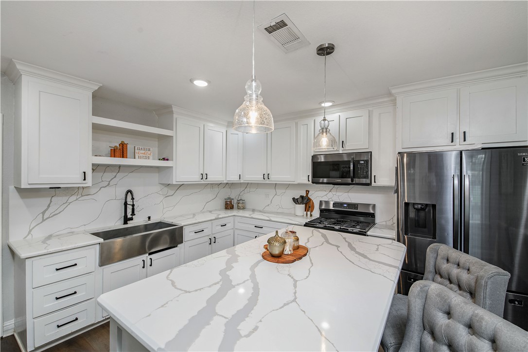 504 Eden Lane Bryan, TX 77803 - Photo 6 of 24 a kitchen with a sink a stove a refrigerator and white cabinets