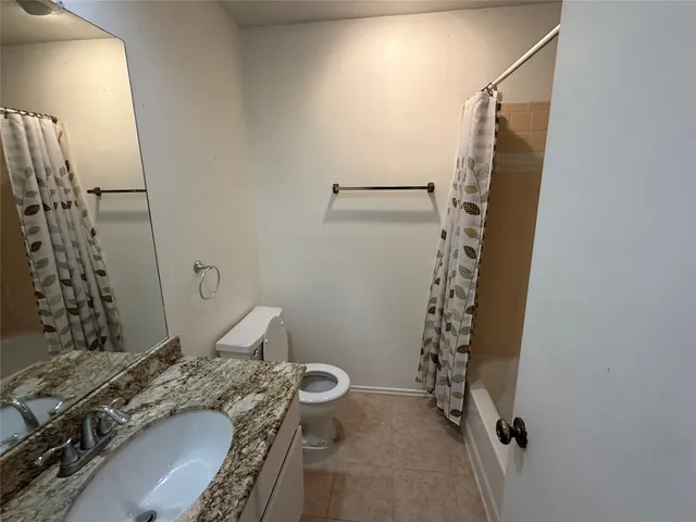 a bathroom with a granite countertop sink a toilet and shower
