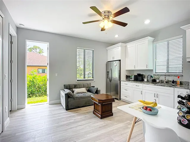 a kitchen with stainless steel appliances granite countertop a refrigerator a stove a sink a dining table and chairs with wooden floor