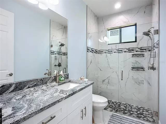 a bathroom with a granite countertop sink toilet and shower