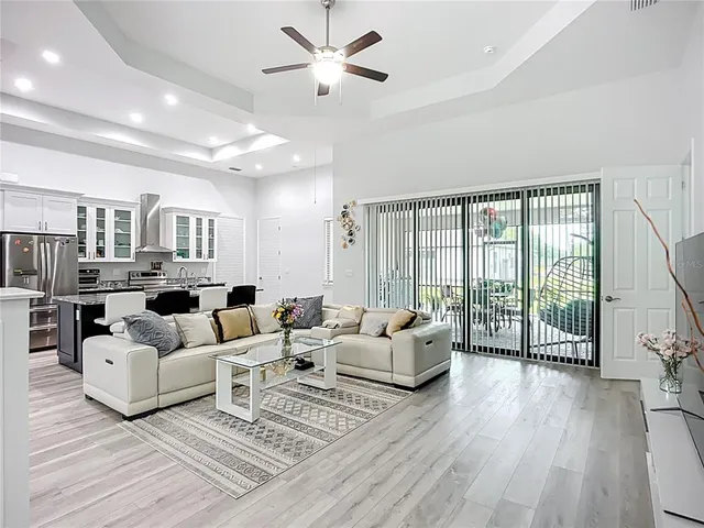 a living room with furniture large windows and wooden floor