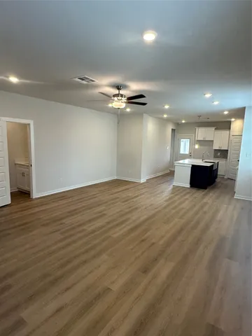 an empty room with wooden floor and a ceiling fan
