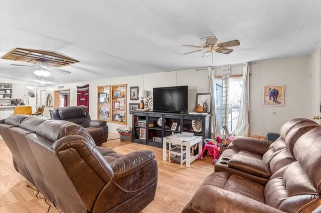 a kitchen with stainless steel appliances kitchen island granite countertop a refrigerator a stove a sink and white cabinets with wooden floor