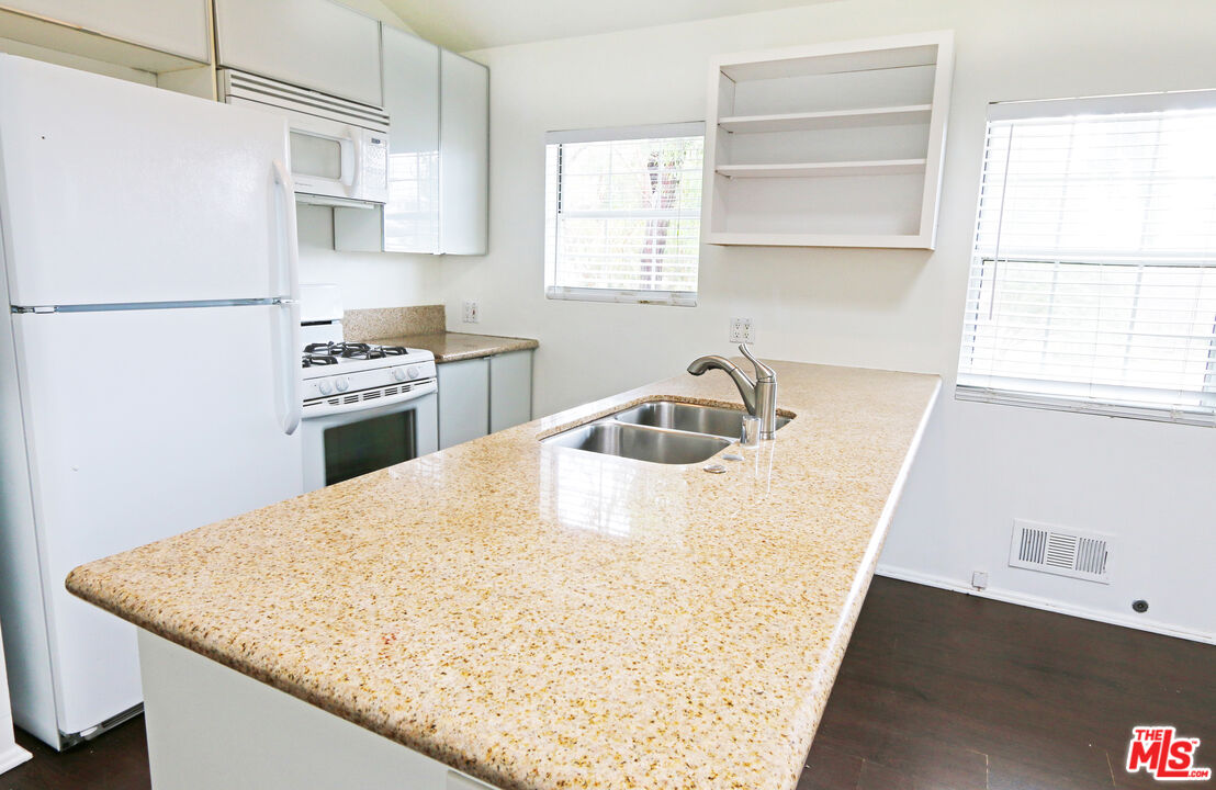 6557 Wandermere Road, Unit GH Malibu, CA 90265 - Photo 11 of 17 a kitchen with a sink a stove a refrigerator and white cabinets