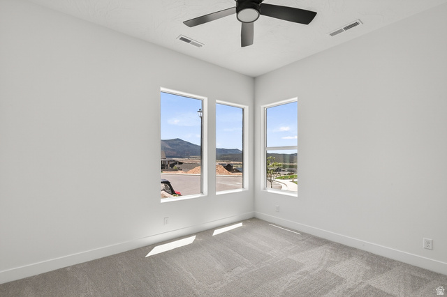 2862 South Mountain Rnch Road Cedar City, UT 84720 - Photo 36 of 64 Spacious room featuring three vertical windows, light gray carpeting, and a modern ceiling fan