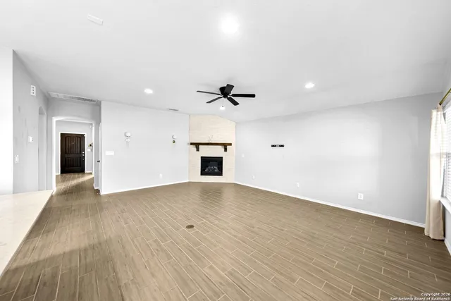 an empty room with wooden floor fireplace and windows