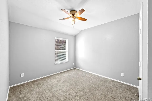 an empty room with window and ceiling fan