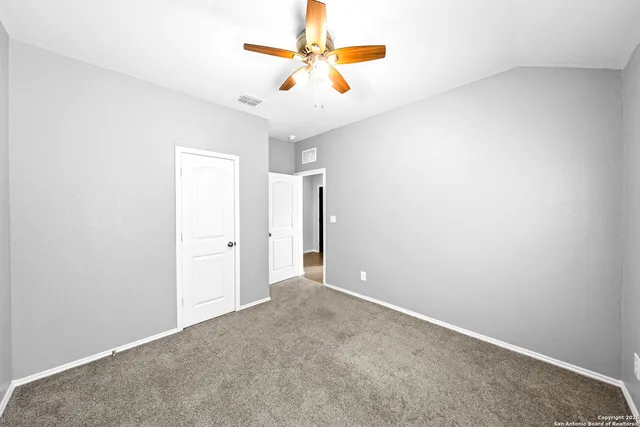 an empty room with closet and a chandelier fan