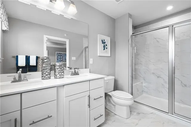 a bathroom with a toilet a sink a mirror a shower a vanity and window