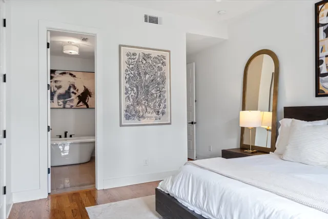 a bedroom with a bed a mirror and a potted plant