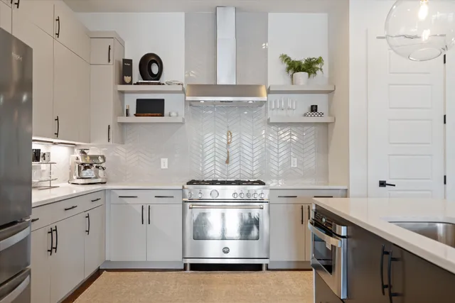 a kitchen with stainless steel appliances a stove and white cabinets