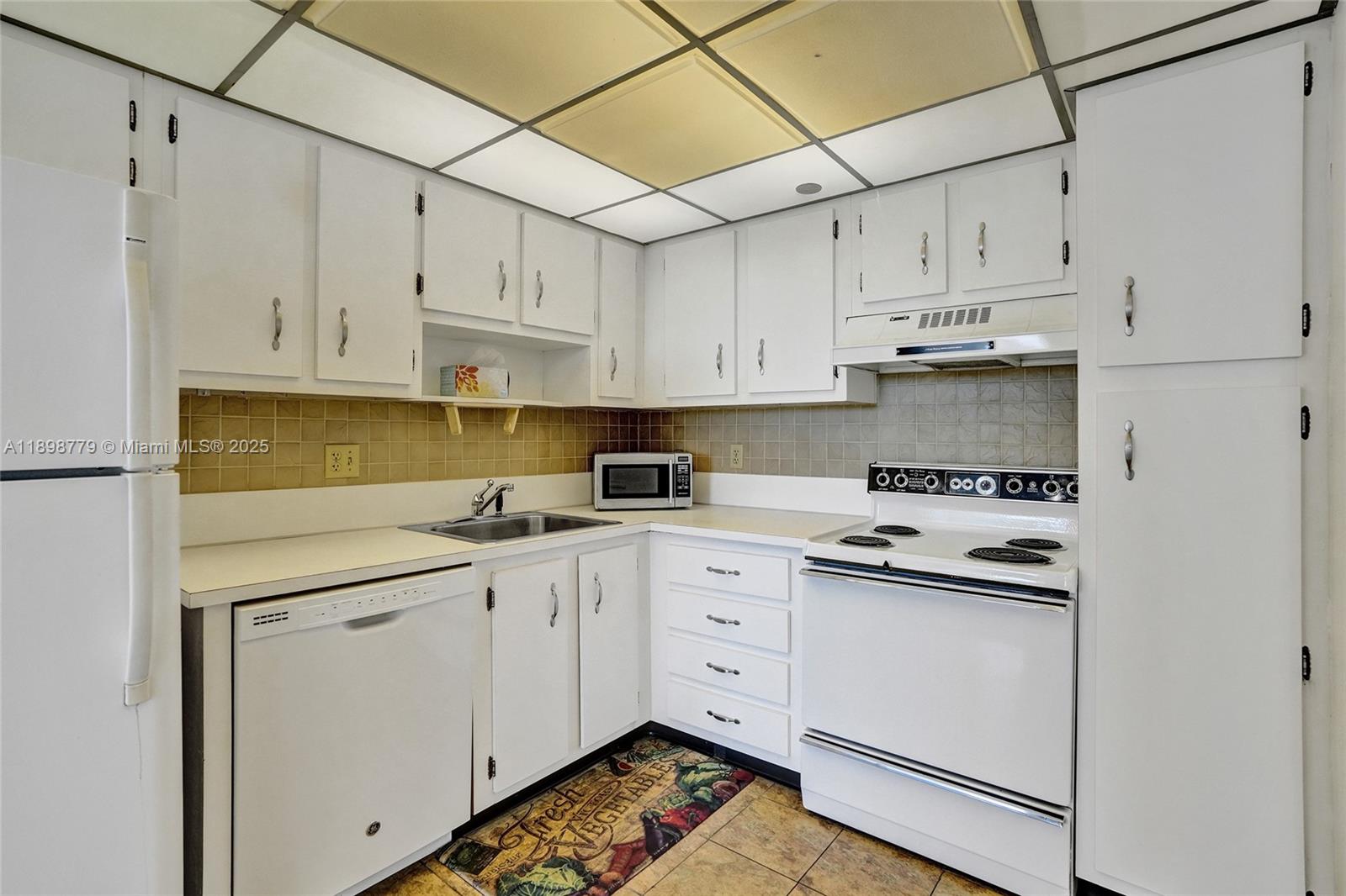 1200 St Charles Place, Unit 413 Pembroke Pines, FL 33026 - Photo 5 of 34 a kitchen with white cabinets and white appliances