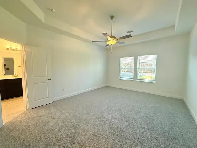 an empty room with a chandelier fan and windows