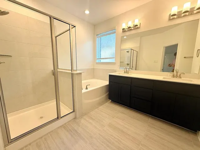 a bathroom with a double vanity sink a mirror and a bathtub
