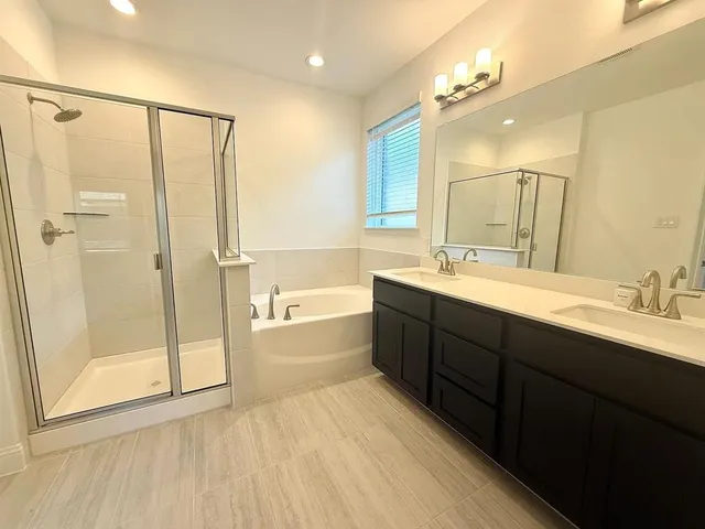 a spacious bathroom with a tub sink shower and mirror