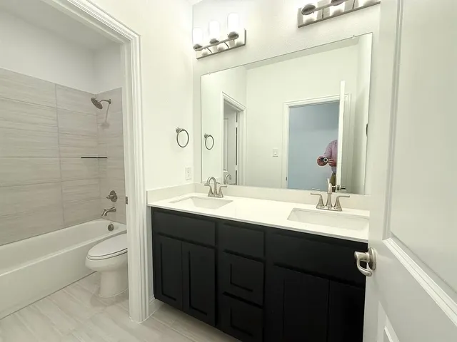 a bathroom with a double vanity sink toilet mirror and bathtub