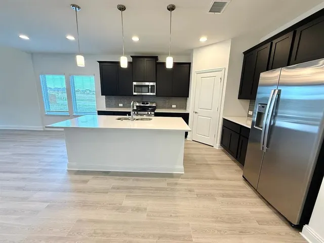 a large kitchen with stainless steel appliances kitchen island a large counter top a refrigerator and a fireplace