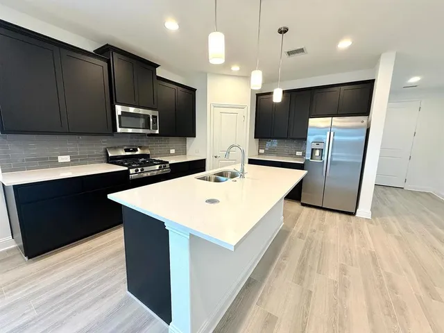a kitchen with stainless steel appliances kitchen island granite countertop a sink a stove and a refrigerator