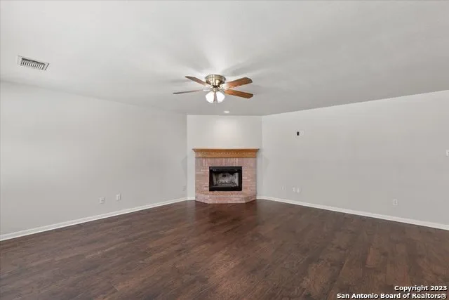 a view of an empty room with a fireplace and a ceiling fan