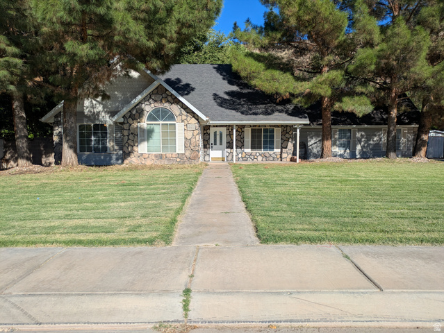 441 Main Street Hurricane, UT 84737 - Photo 1 of 29 Stone facade with arched window, columned front porch, and mature trees framing the property
