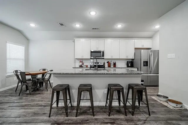 a kitchen with granite countertop white cabinets and stainless steel appliances