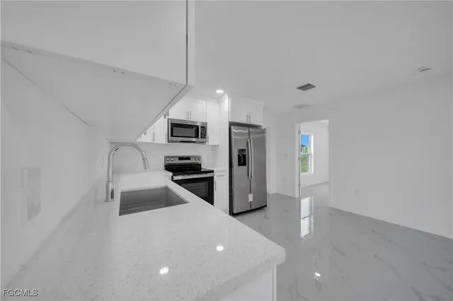 a kitchen with granite countertop a sink a counter space stainless steel appliances and cabinets