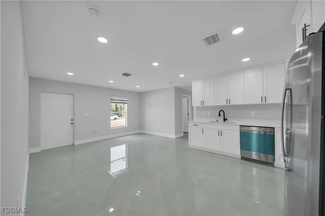 a large kitchen with stainless steel appliances lots of white cabinets