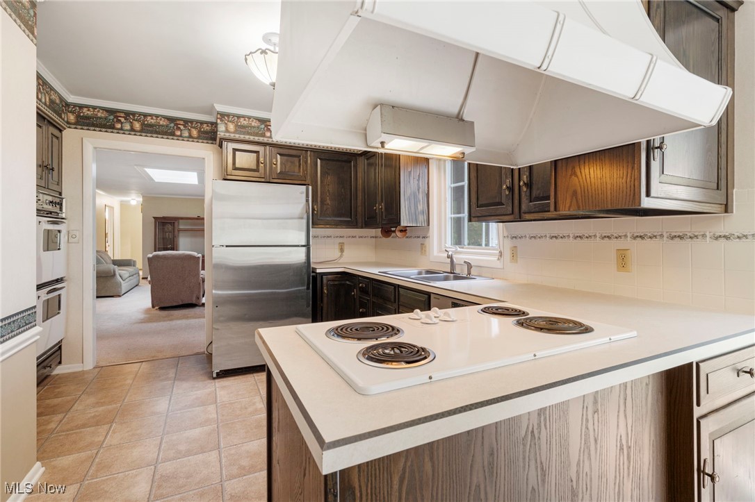 14265 Reeder Avenue Northeast Alliance, OH 44601 - Photo 21 of 39 Kitchen featuring under cabinet range hood, light countertops, white appliances, a peninsula, and light tile patterned flooring