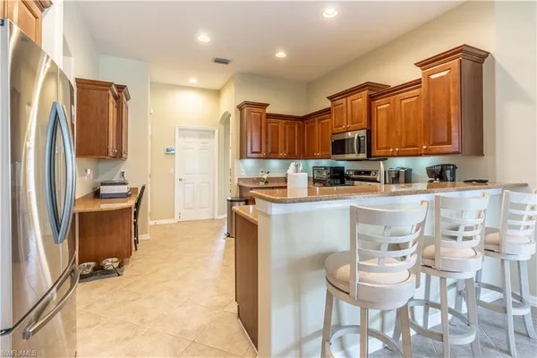 a kitchen with kitchen island granite countertop wooden cabinets a refrigerator and a stove