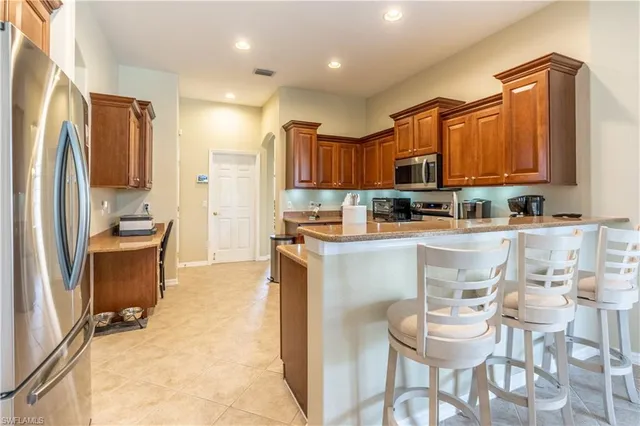 a kitchen with kitchen island granite countertop wooden cabinets a refrigerator and a stove