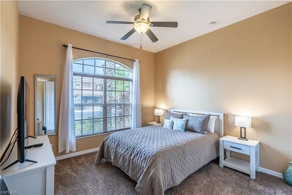 a bedroom with a large bed and a chandelier fan