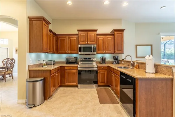 a kitchen with stainless steel appliances granite countertop a stove top oven a sink dishwasher a dining table and chairs with wooden floor