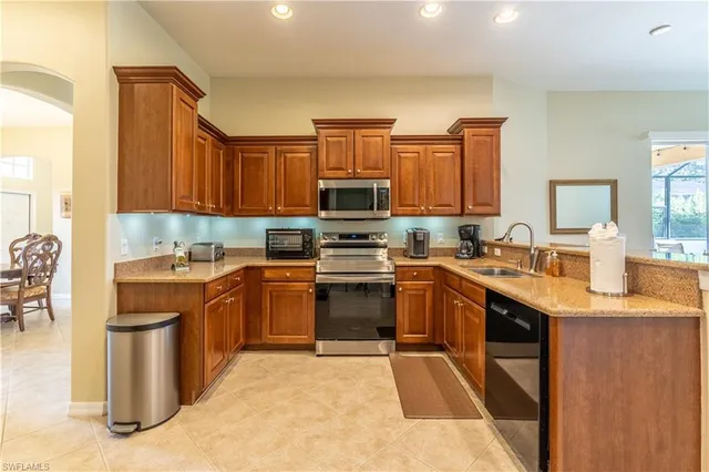 a kitchen with stainless steel appliances granite countertop a stove top oven a sink dishwasher a dining table and chairs with wooden floor