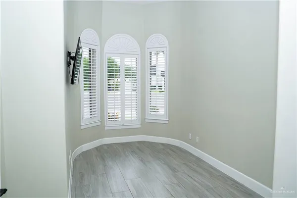 a view of empty room with wooden floor and window
