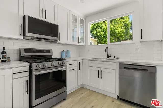a kitchen with cabinets stainless steel appliances a sink and a window