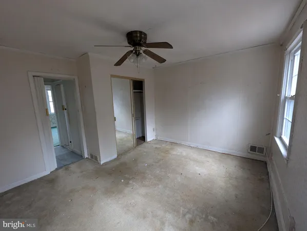 an empty room with windows and fan