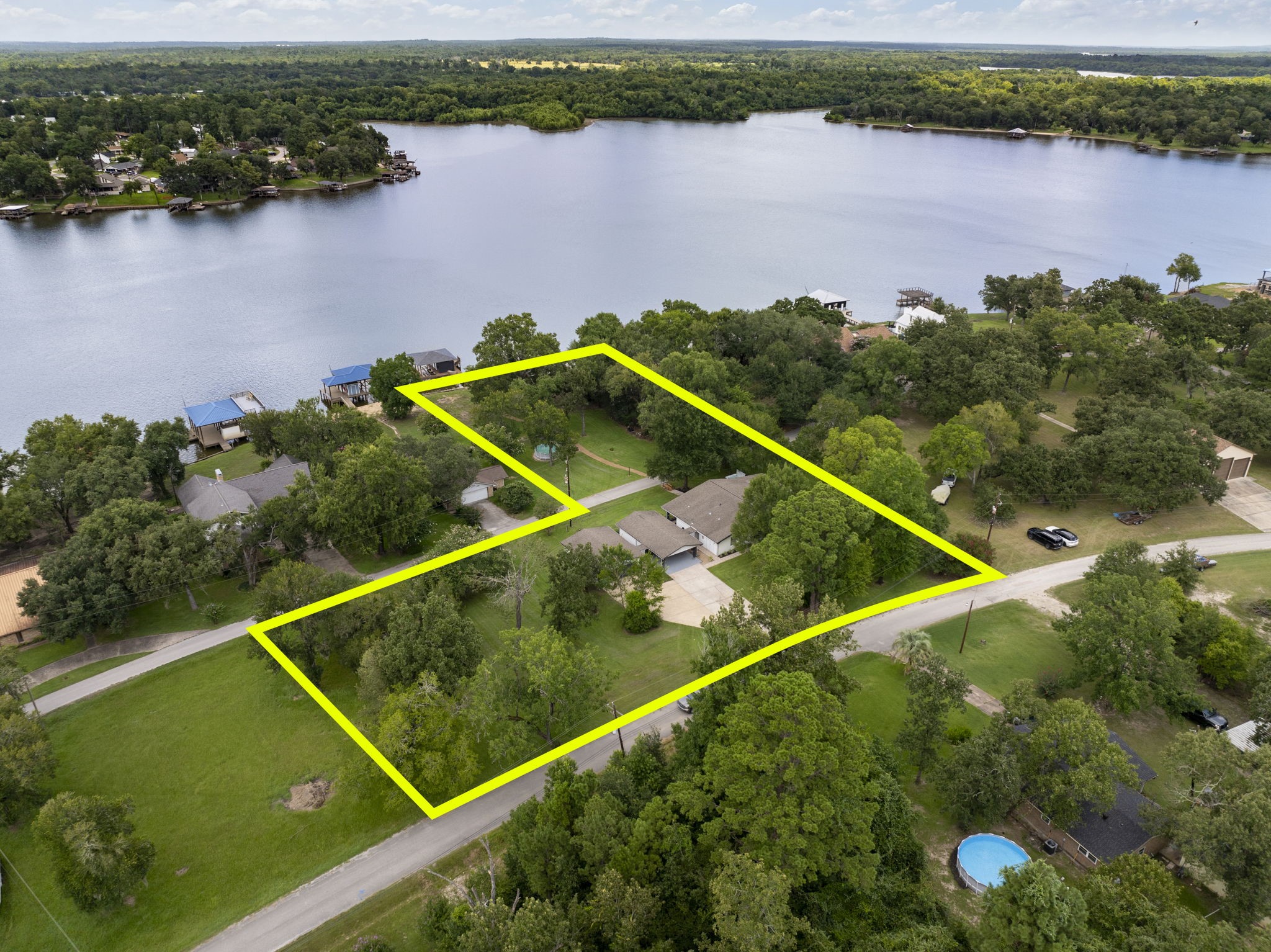 245 Lakeland Road Huntsville, TX 77320 - Photo 1 of 49 Experience a breathtaking aerial view of this stunning property, showcasing its expansive layout with waterfront lot and boat house.