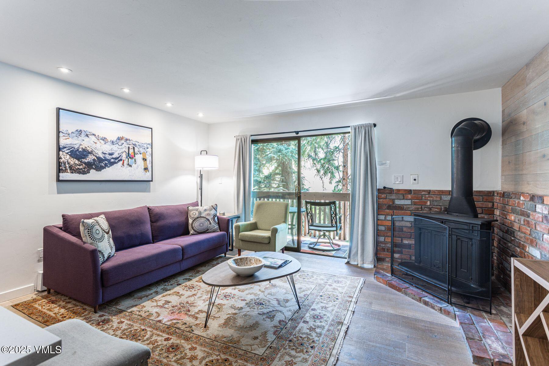 4630 Vail Racquet Club Drive, Unit 15 Vail, CO 81657 - Photo 2 of 20 a living room with furniture a fireplace and a floor to ceiling window