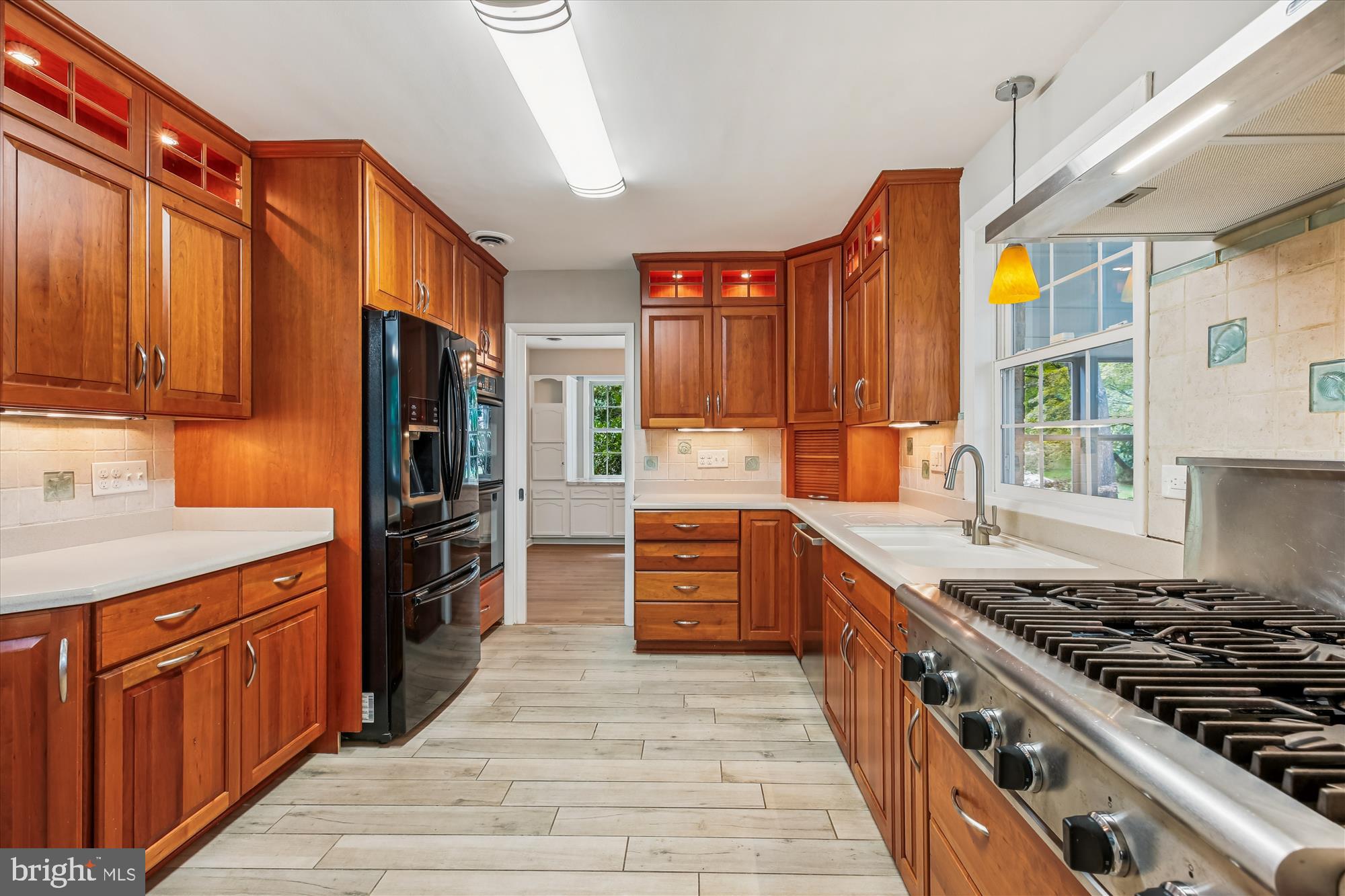 a kitchen with stainless steel appliances granite countertop a stove top oven a sink dishwasher a refrigerator and cabinets with wooden floor