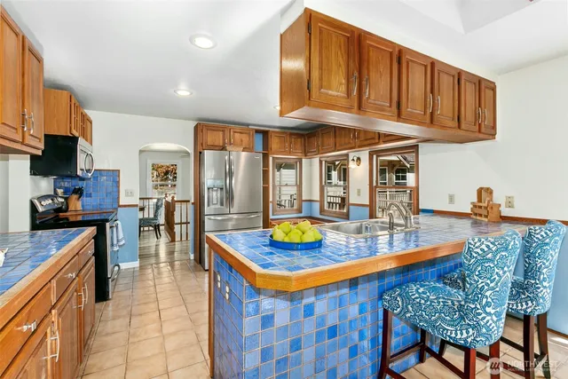 a kitchen with stainless steel appliances granite countertop a sink a stove and a wooden cabinets