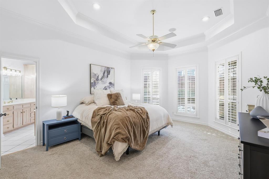 117 Sand Point Court Coppell, TX 75019 - Photo 18 of 40 a spacious bedroom with a bed a dresser and a chandelier
