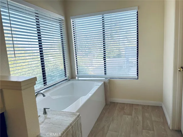 a bathroom with a granite countertop sink and mirror with bathtub