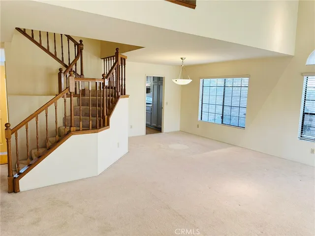 a view of an empty room with stairs and a window