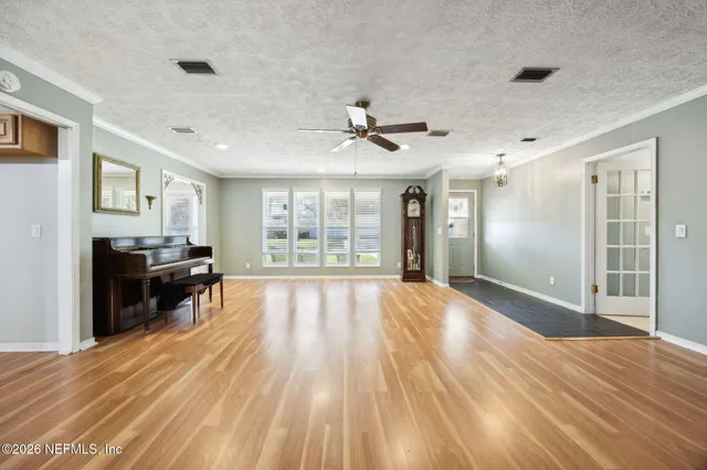 a view of empty room with wooden floor and fan