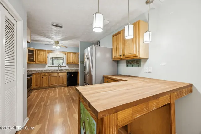 a kitchen with stainless steel appliances kitchen island granite countertop a refrigerator a sink dishwasher with a dining table and chairs