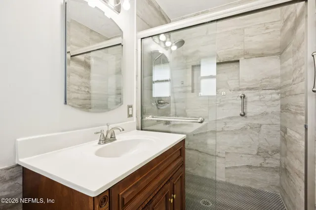 a bathroom with a sink shower and a mirror