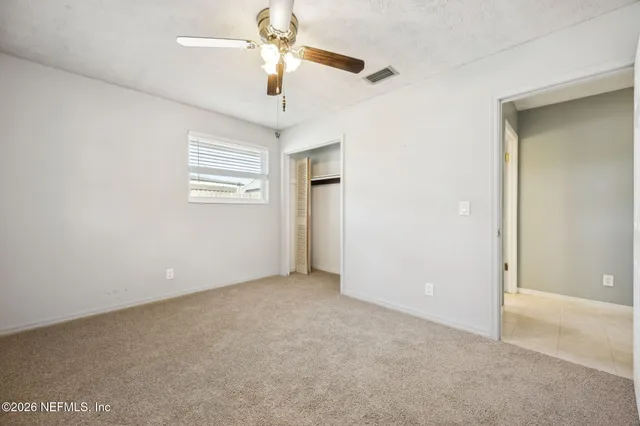 an empty room with windows and fan