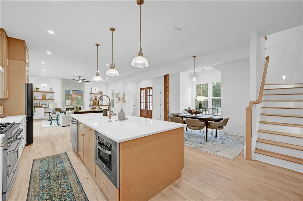2893 Lavista Road Decatur, GA 30033 - Photo 11 of 37 a large kitchen with kitchen island a sink a stove a dining table and chairs with wooden floor